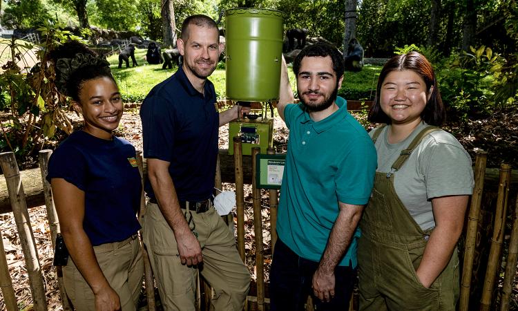 Students and zoo employees beside the gorilla feeder