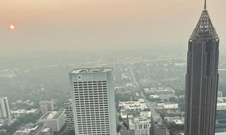 Hazy Atlanta with Bank of America tower and TSI building and a distant, orange sun.
