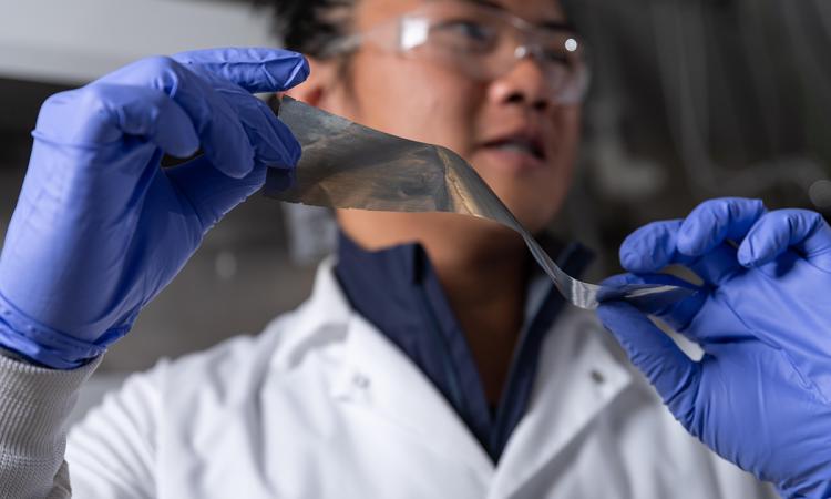 Graduate student researcher Yuhgene Liu holds an aluminum material for solid-state batteries. (Photo: Rob Felt)