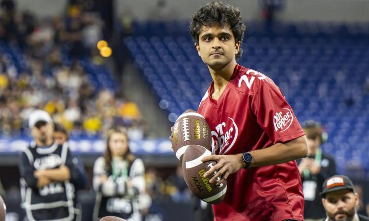Sid Suratia holds two footballs and looks at his target on the field during the Dr. Pepper Tuition Giveaway at the Big 10 Championship game.