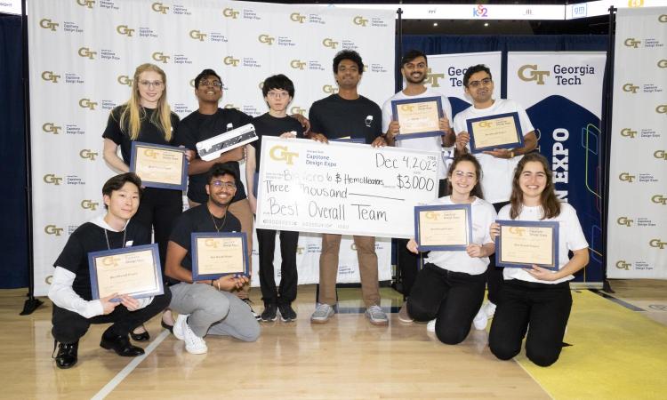 Both winning teams from the Fall 2023 Capstone Design Expo pose with their certificates and oversized check.