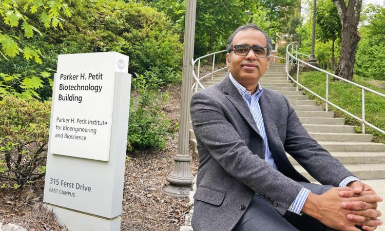 Ankur Singh sits outside next to the Parker H. Petit Biotechnology Building sign