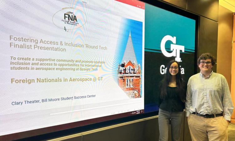 Two members of the winning FAIR Tech competition team, Jasrayman “Ray” Thind and Alfonso Lagares de Toledo, stand at a screen displaying the title slide of their final presentation.