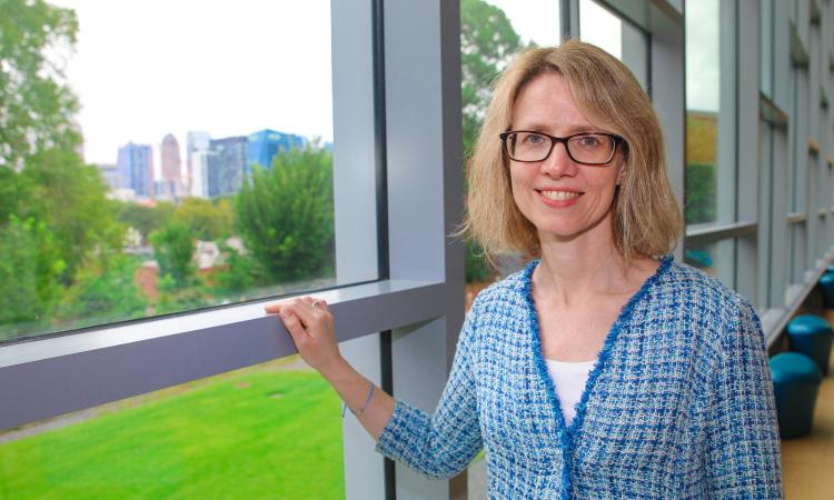 Martha Grover stands at a window overlooking campus and the Atlanta skyline