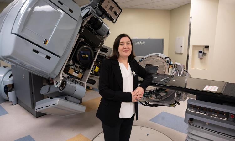 Anna Erickson stands in her lab with a large medical linear accelerator. (Photo: Joya Chapman)