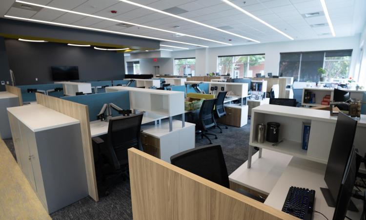 Open workspace with cubicles and computer monitors as well as a break and kitchen area.