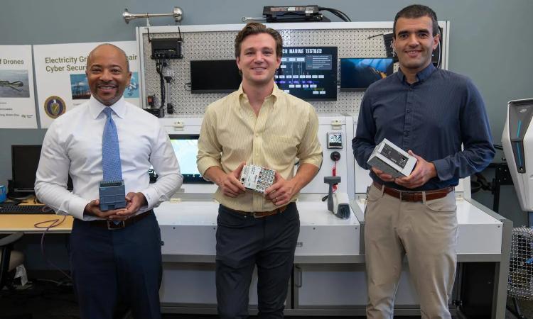 Raheem Beyah, Ryan Pickren, and Saman Zonouz holding a variety of programmable logic controllers used in many industrial and critical infrastructure systems.