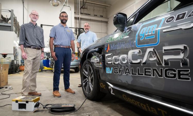 ECE and ME researchers next to the Georgia Tech EcoCAR Challenge vehicle with their smart EV charging system connected to its charging port.