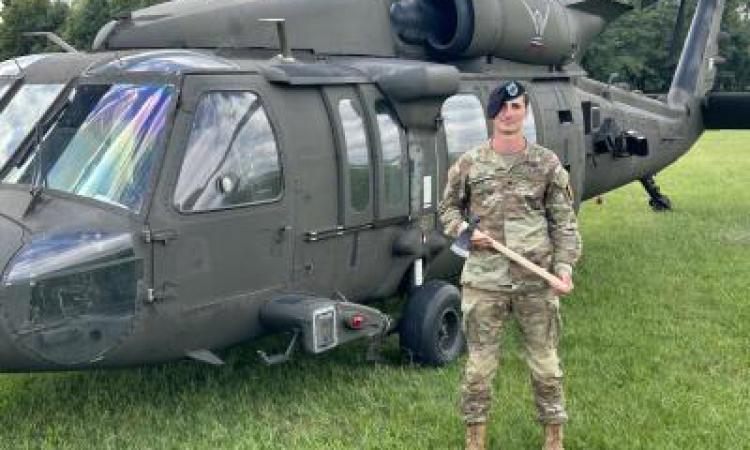 Mason Ladd in fatigues standing next to a military helicopter.