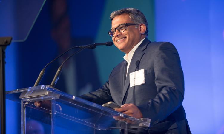 Side view of Suman Datta standing at a podium and smiling