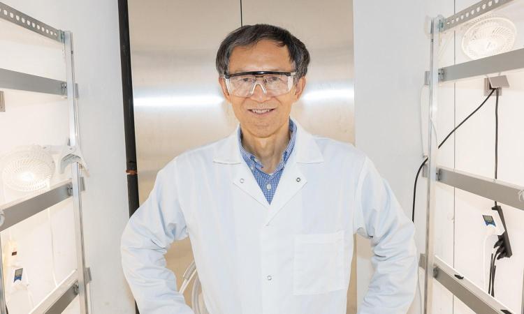 Yongsheng Chen stands his lab with safety glasses and lab coat.