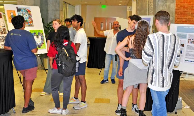 Students presenting their art created in partnership with AI during a final exhibition in the Mason Building lobby.