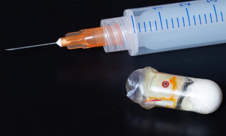 a closeup of a needle next to a new kind of capsule