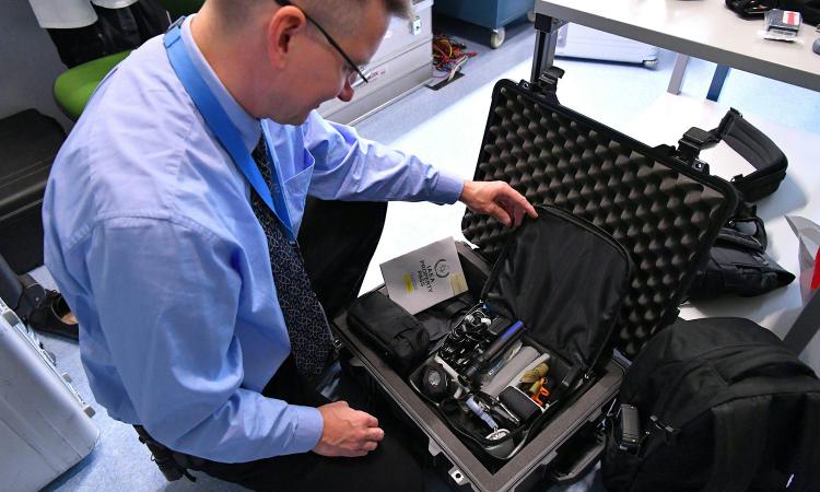A man shows the contents of a travel case with equipment for inspecting nuclear facilities. (Photo courtesy: Dean Calma/IAEA)