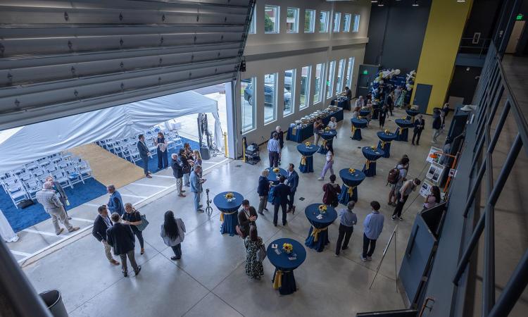 Inside the new Aircraft Prototyping Lab after the ribbon cutting with people milling around tables set up in the high bay area.