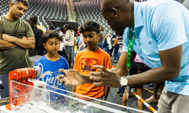 two children watch waves in a tank at STEM Fest