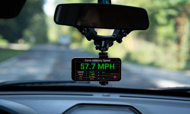 A smartphone mounted on a car dashboard shows a calculated curve advisory speed during tests in Forsyth County, Georgia.