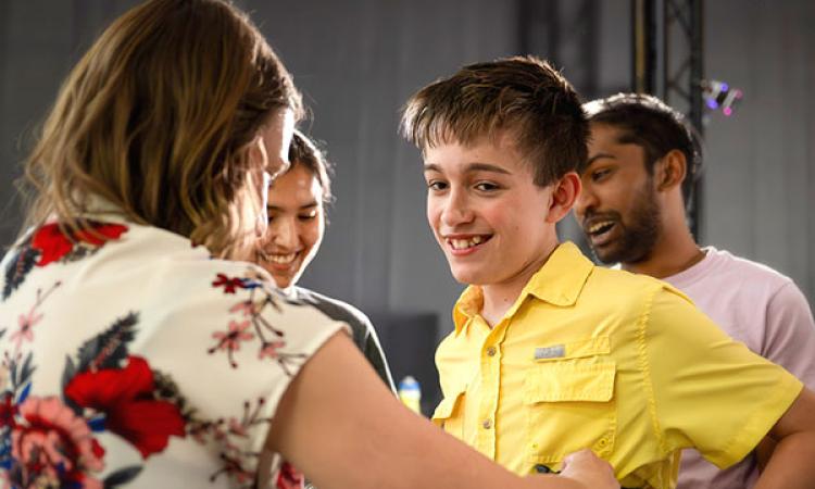 Case Neel smiles while a researcher adjusts a harness before tests using a robotic exoskeleton.