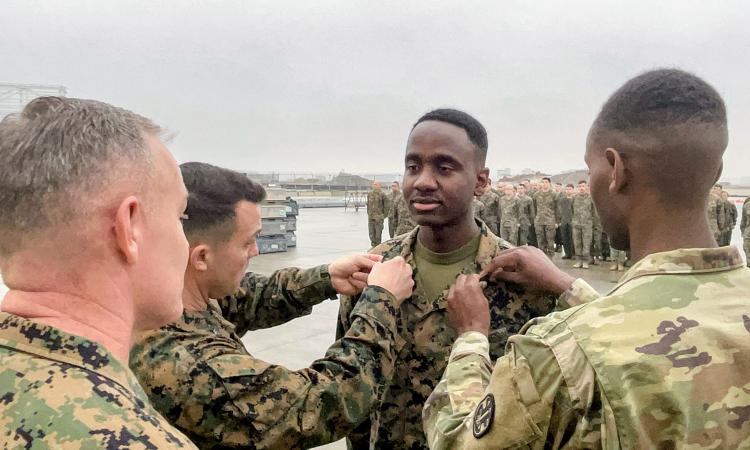 Thomson Maina with his brother and his senior officer during a ceremony promoting him to sergeant.