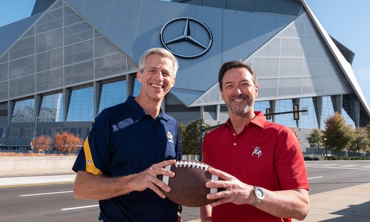 Georgia Tech and UGA research leaders Tim Lieuwen and Chris King pose with a football outside Mercedes-Benz Stadium in Atlanta.
