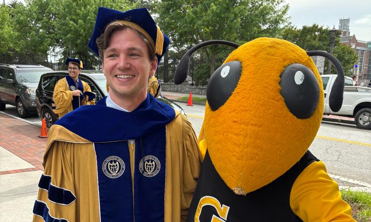 Ryan Pickren in Ph.D. regalia with Buzz
