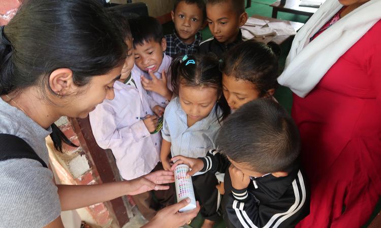 A student shows water testing strips to a group of children in Chisopani Bhirkhe, Nepal.