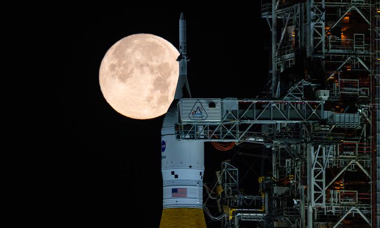The Orion spacecraft atop the SLS rocket with the moon behind it (Credit: NASA/Sam Lott)