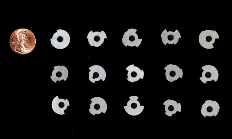 A group of 15 metal tags of various shapes and a penny to show the tags are smaller.