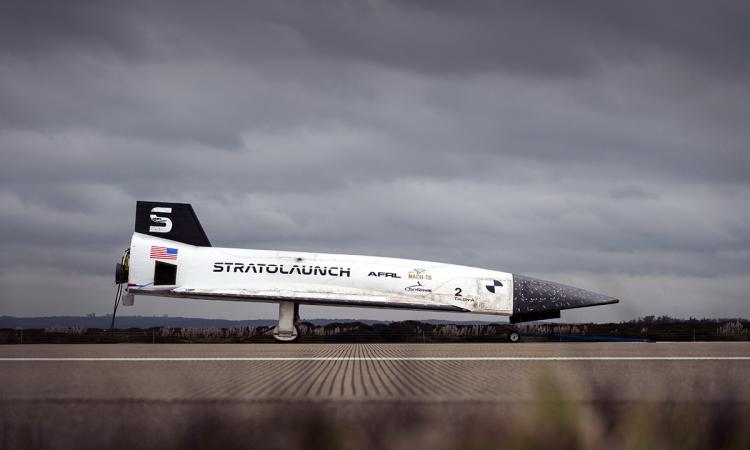 a hypersonic vehicle sits on a tarmac with dark clouds in the background