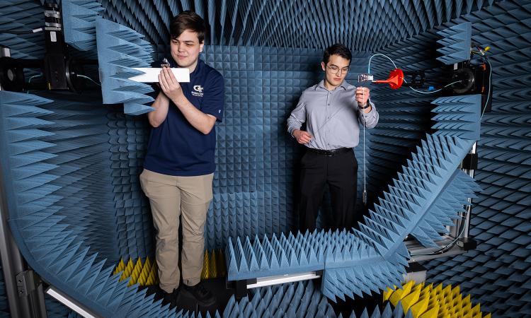 two people work in a chamber with antenna equipment