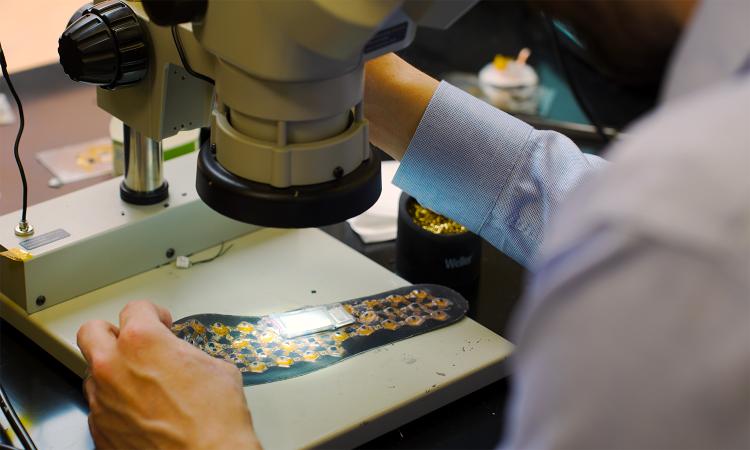 Matthew Flavin looks at a shoe insole with pressure sensors under a microscrope.