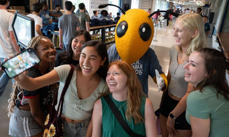 Buzz takes a selfie with a group of students