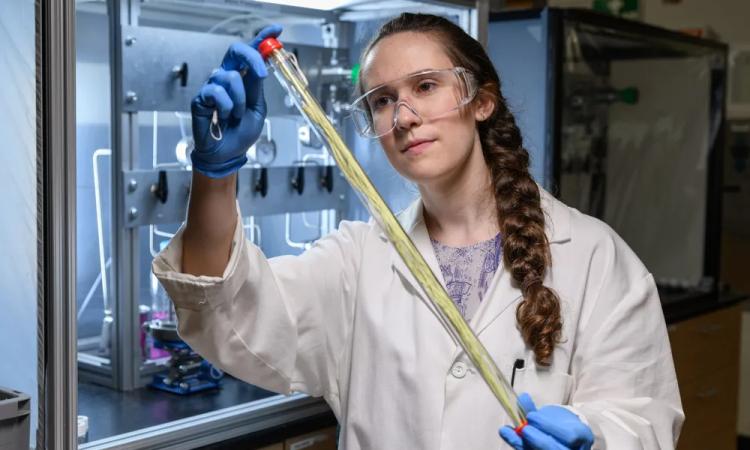 A graduate student examines a hollow fiber membrane used for low-energy chemical separation.