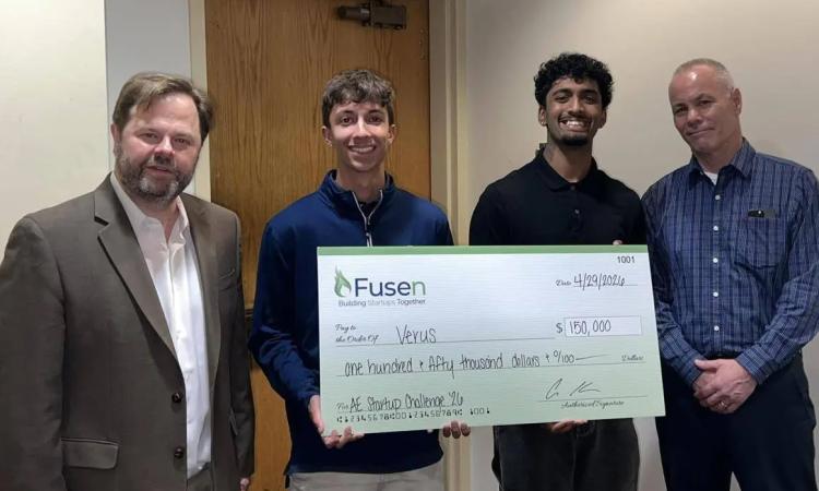 Students Taran Govindu and Aiden Erard and competition organizers pose with an oversized check.
