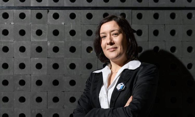 Anna Erickson standing in front of Antineutrino Detection, photo.