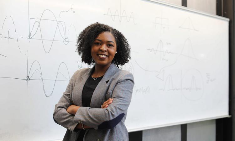 Quinnell Smith standing in front of a white board, photo