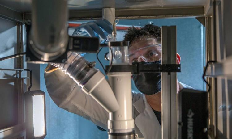 Grad student adjusting equipment designed to sample building air 