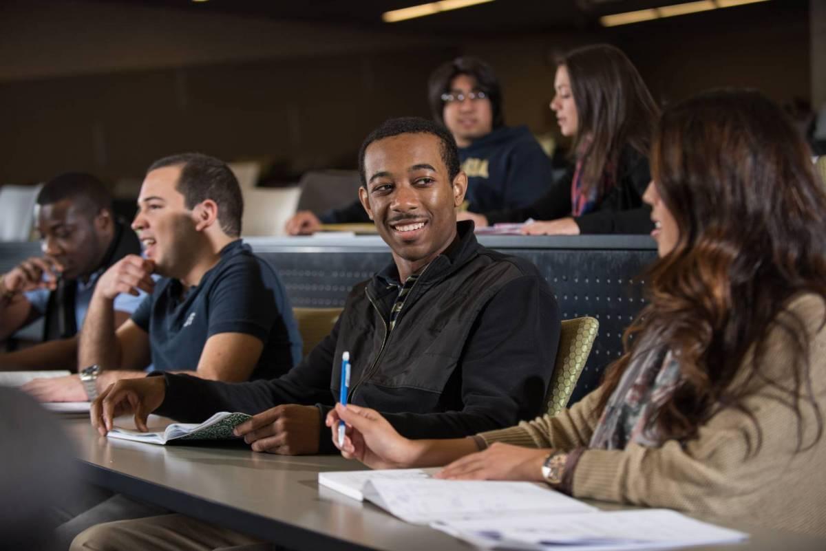 Three students listening in a lecture hall.