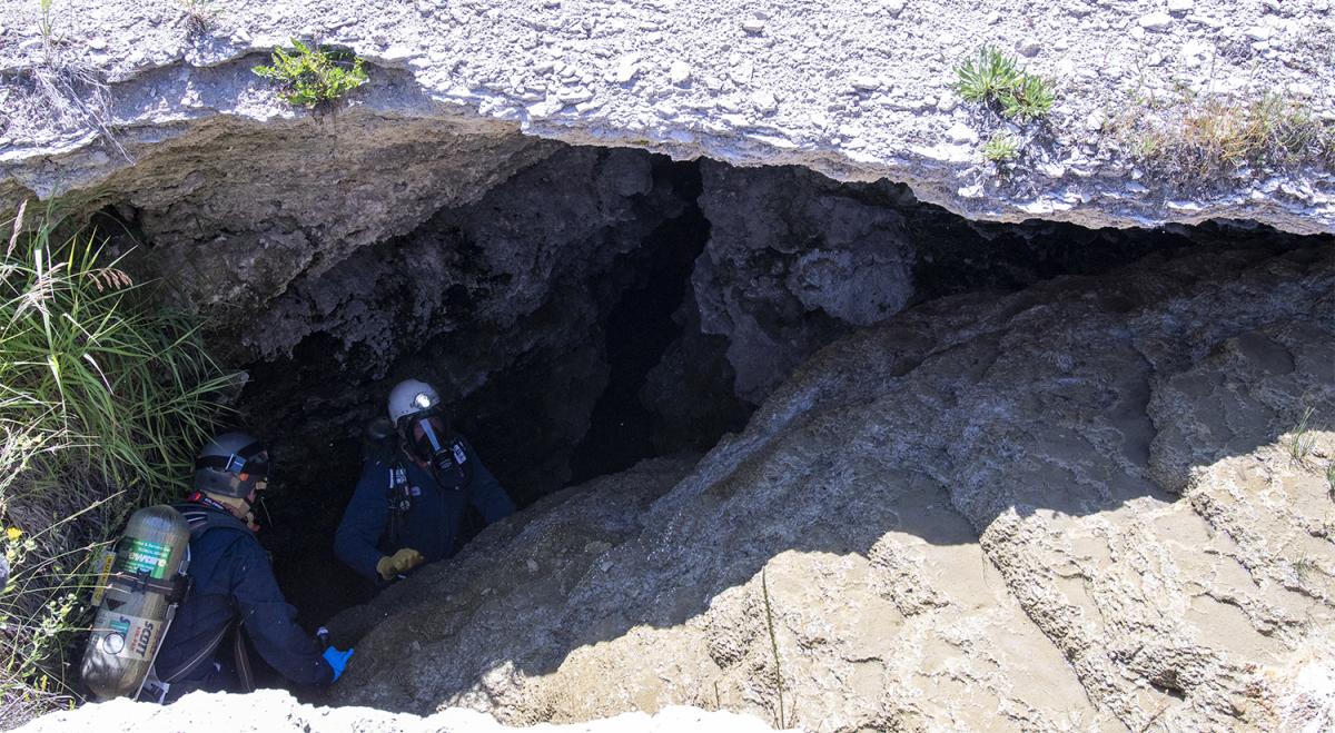 two people climbing into a cave