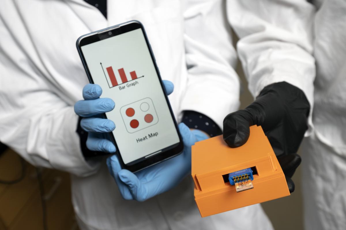 Closeup of the microchip in the multimeter and the custom smartphone app displaying the test results