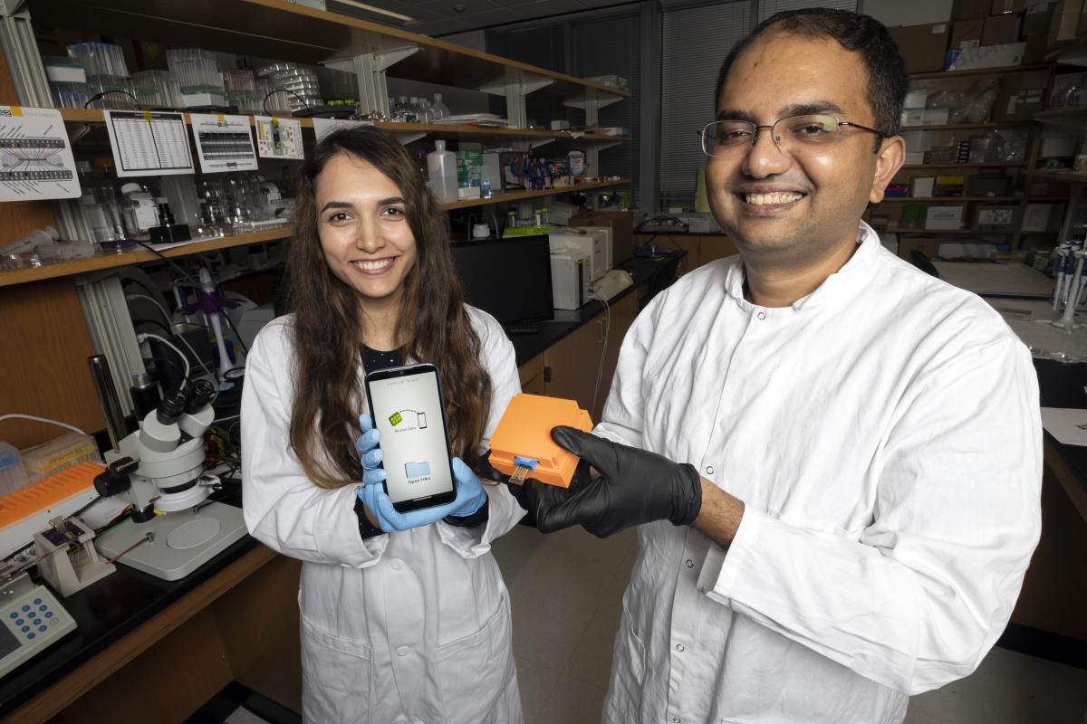 Posdoctoral fellow Neda Rafat and Assistant Professor Aniruddh Sarkar demonstrate the microchip in the multimeter and the custom smartphone app that displays the results