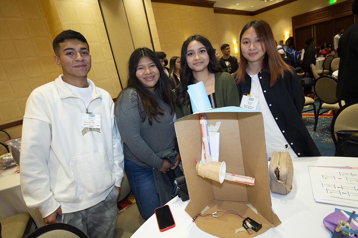 A group of four students with their cardboard funhouse design.