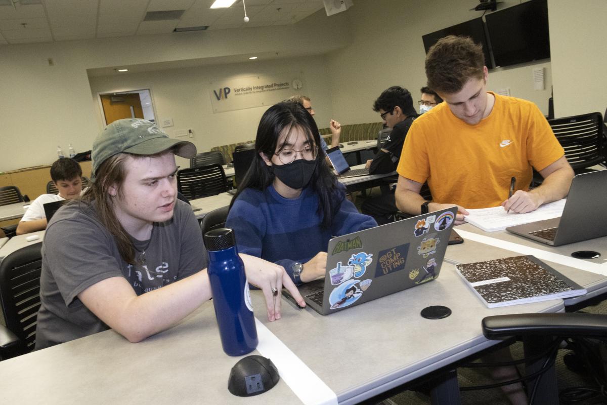 Three VIP students work on a laptop