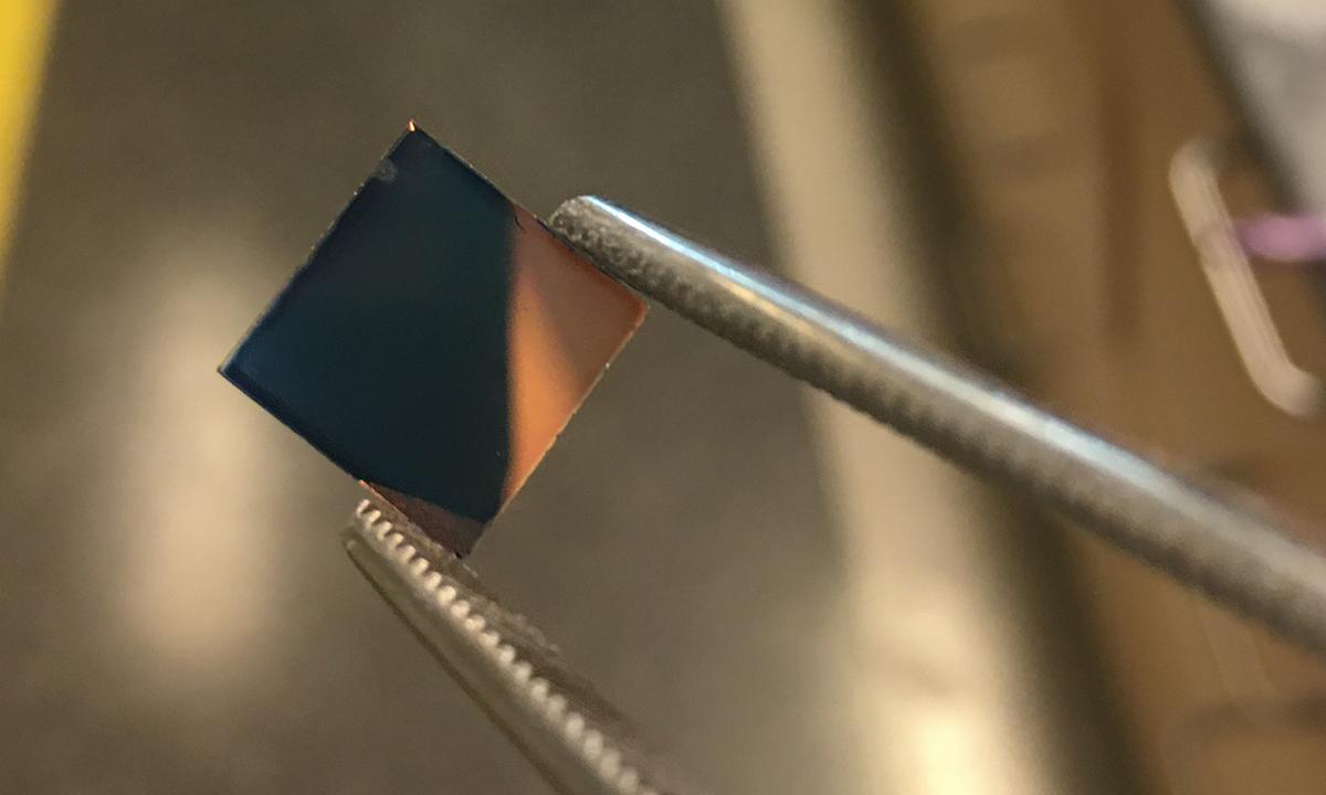A bluish square of the PEDOT polymer held by a pair of tweezers. The polymer is initial this bluish tint when it's cast a film. Further processing results in a highly conductive, transparent plastic. (Photo Courtesy: James Ponder)
