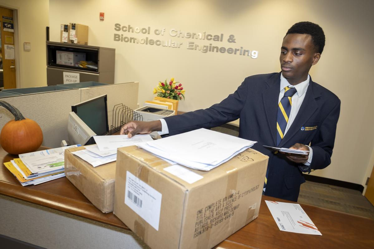 A student sorts mail and packages at a front desk 