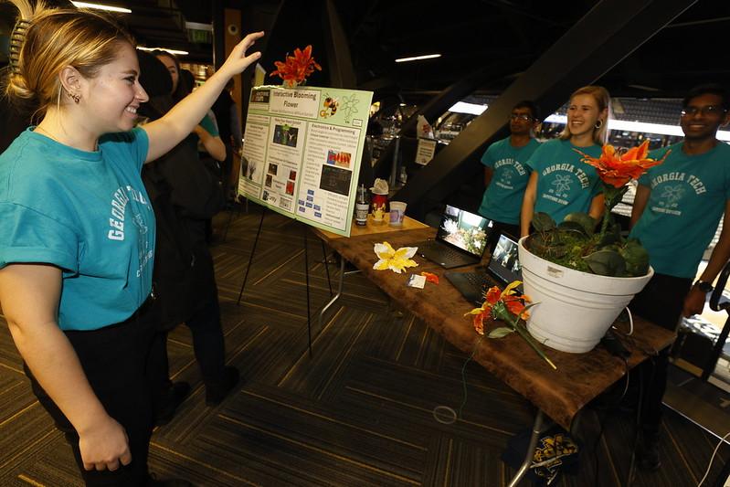 student holds out arm to control a flower