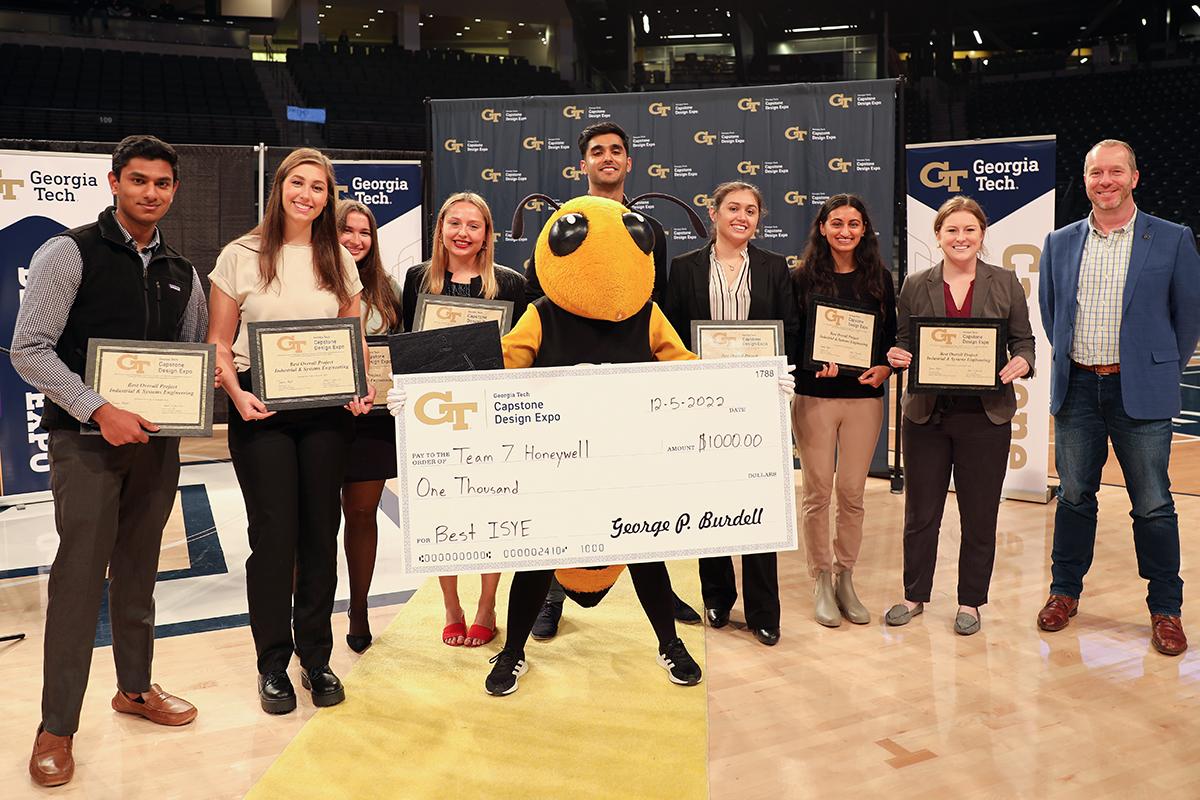 eight people comprising Team Honeywell pose with Buzz, School Chair Edwin Romeijn, and the winning check.