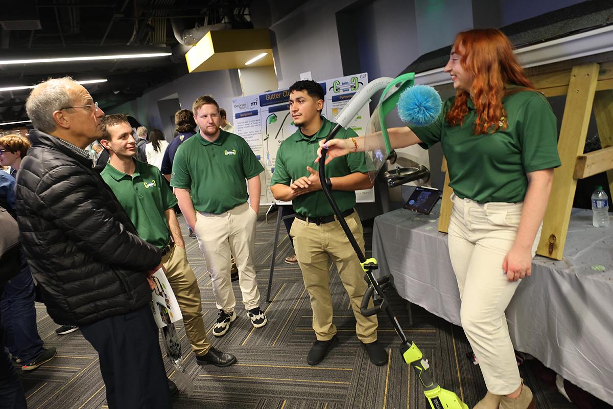 students tell an attendee about their gutter cleaning tool