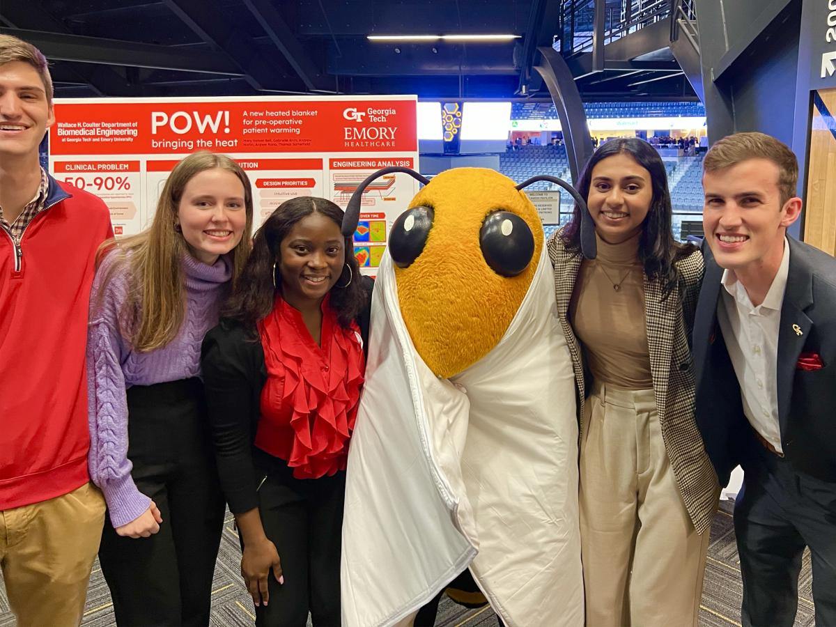 a group of students with mascot Buzz in front of a poster at the Capstone Design Expo