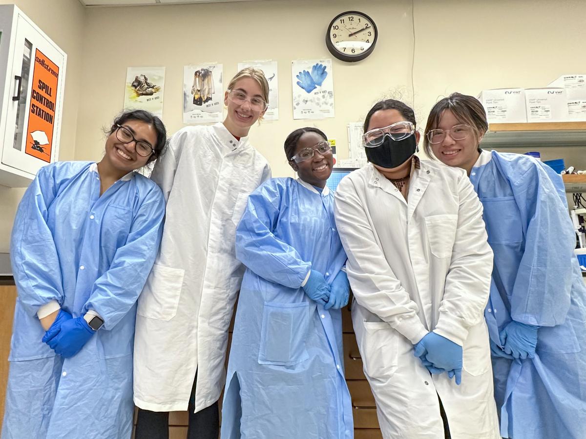 A group of students wearing lab coats and goggles in a lab
